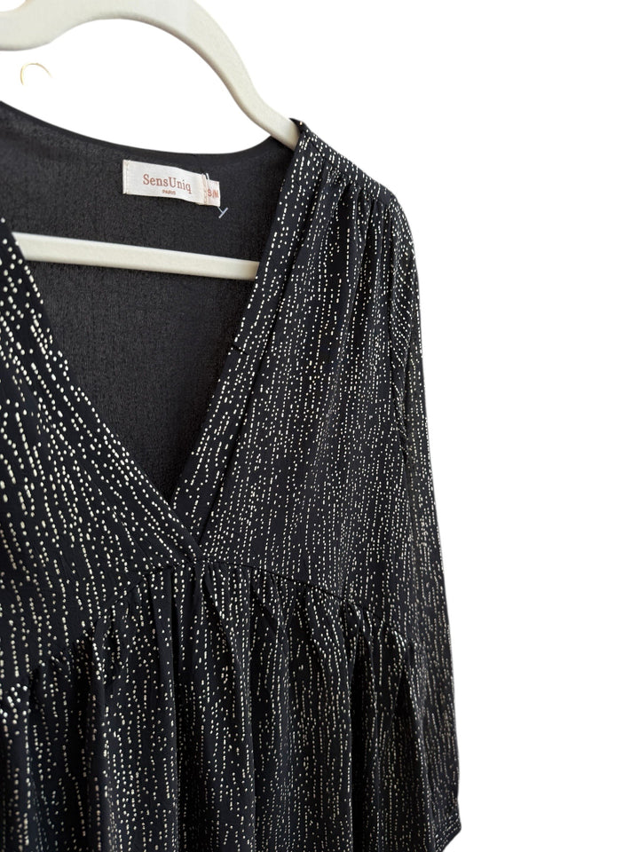 Retrend black fluid dress with subtle gold dotted print, V-neck, empire waist, long sleeves, and ruffled hem. Size S/M.