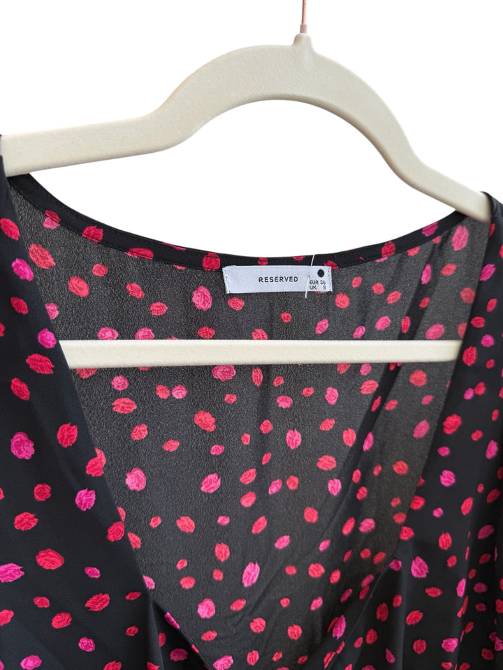 ReTrend black flowing dress with red and pink irregular polka dots, V-neck, tie detail, and ruffled hem. Size 36.