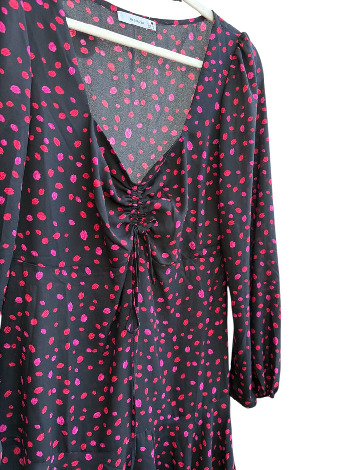 ReTrend black flowing dress with red and pink irregular dots, deep V-neck, ruched tie detail, long sleeves, and ruffled hem. Size 36.